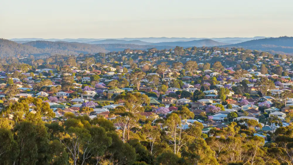 View from a ridge over South East Queensland suburbs rolling to distant blue ranges
